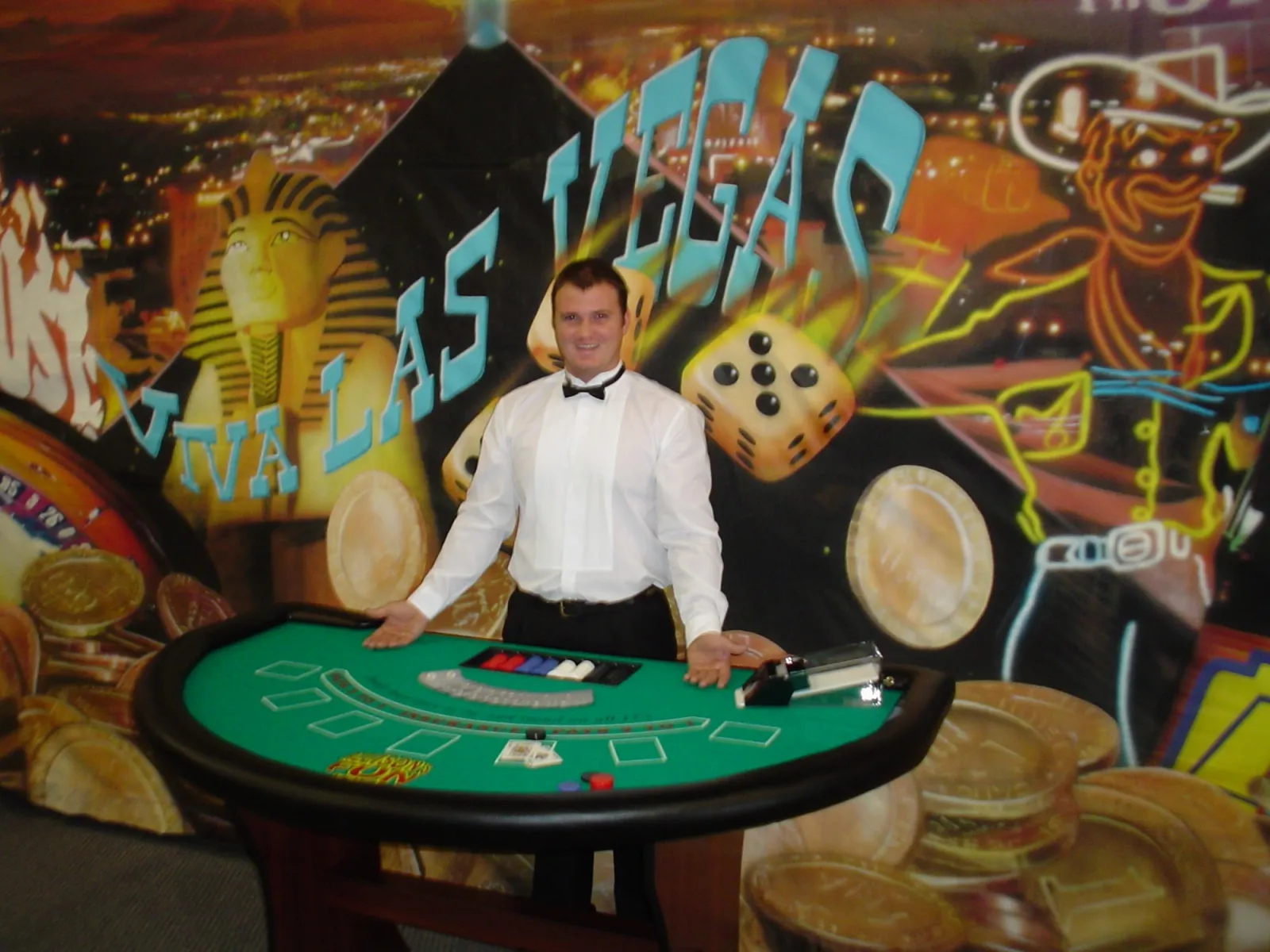 Blackjack table rental with a tuxedoed dealer in front of a Viva Las Vegas backdrop at a casino party in Oklahoma