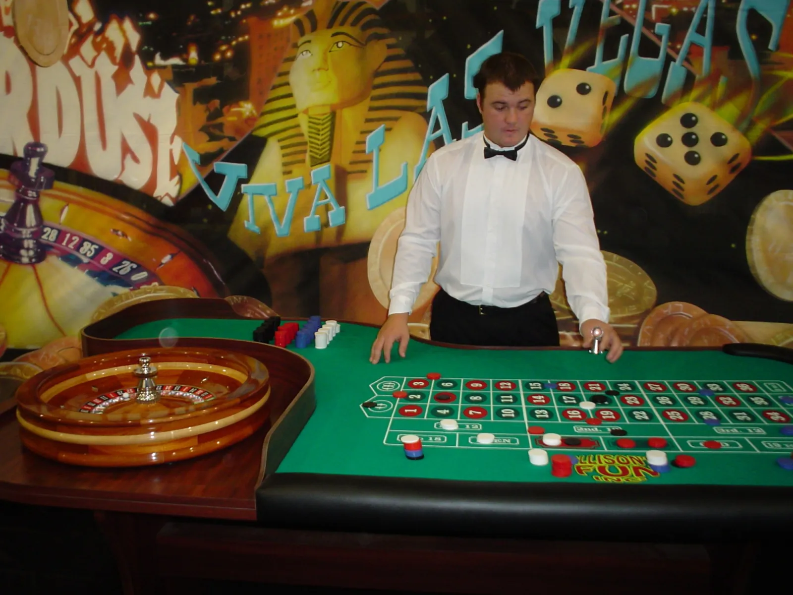 Roulette table rental with a wooden roulette wheel, chips and a dealer at a casino party