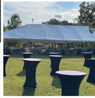 High-top cocktail tables with black spandex covers in front of a frame tent