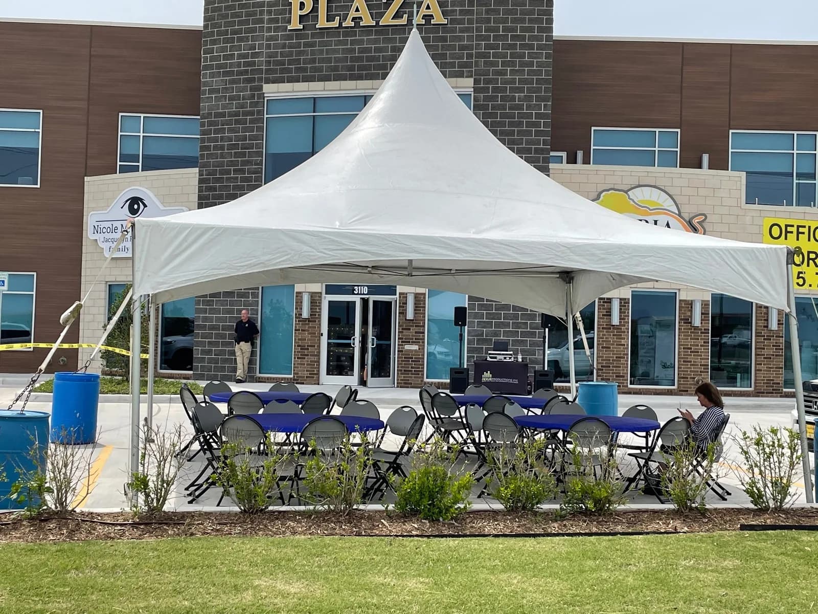 Round tables with blue linens and folding chairs under a 20x20 high peak party tent